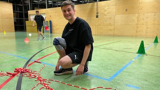Lukas Rohfleisch kniet vor Springseilen in der Sporthalle vom TS Ottersweier. Er trainiert für die nächste Meisterschaft im Rope Skipping.