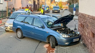 Ein Auto hat eine schwer beschädigte Motorhaube und ist gegen eine Wand gefahren.