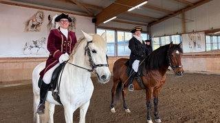 Reiterinnen und prunkvollen Kostümen sitzen auf ihren Pferden im Barockreitzentrum Heimsheim.