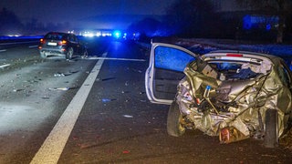 Zwei Unfallautos stehen auf der nächtlichen Autobahn, auf der die Trümmer der Kollission verteilt sind.