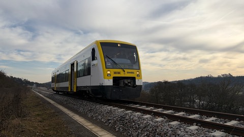 Eine Bahn fährt auf Schienen entlang.