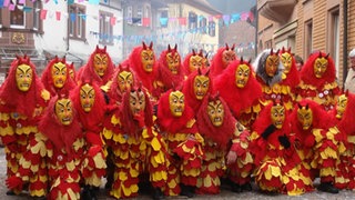 In Holzmasken und rot-gelben Narrenhäs: Die Maskengruppe der Fürig Barthel aus Hörden ist auf einem Umzug unterwegs.