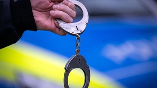 Handschellen vor Polizeiauto