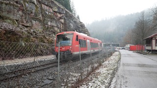 Ein roter Waggon der Kulturbahn fährt entlang einer Felswand