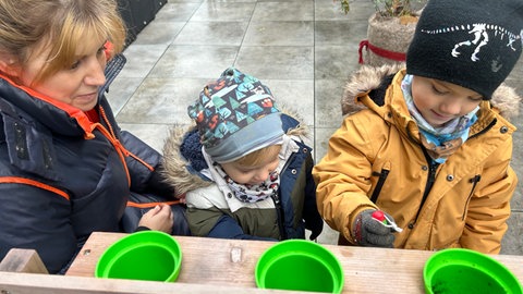 Kinder spielen mit ihrer Mutter mit einer Spielküche im Garten in Durmersheim. Sie können wegen eines Brandes nicht in ihre Kita.