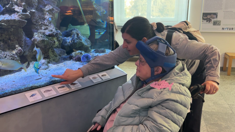 Eine Betreuerin zeigt einer Demenzpatientin die Fische im Naturkundemuseum Karlsruhe. 