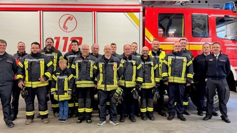 Feuerwehrleute vor einem Feuerwehrfahrzeug.