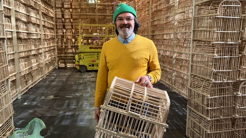 Karlsruher Künstler Fahar Al-Salih steht in der Stadtkirche mit einem Vogelkäfig in der Hand.
