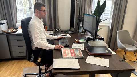 Der Neuenbürger Bürgermeister Fabian Bader sitzt an einem Schreibtisch. Er kämpft für das Krankenhaus der Gemeinde.
