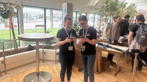 Lisa und Lara (v.l.n.r) Friedrich schauen auf ihr Smartphone und prüfen die Puzzle-Motive