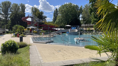 Wellenbecken und Wasserrutschbahn des Freibads Rheinstrandbad Rappenwört in Karlsruhe neben der Liegewiese am Rhein.