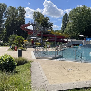 Wellenbecken und Wasserrutschbahn des Freibads Rheinstrandbad Rappenwört in Karlsruhe neben der Liegewiese am Rhein.
