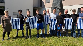 Eine Gruppe posiert mit Fußballtrikots.