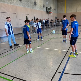 Eine Gruppe straffälliger Jugendlicher aus der Jugendeinrichtung Schloss Stutensee steht im Kreis und kickt mit einem Fußball.