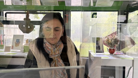 Tanja Kasper blickt auf das Foto ihres Großvaters und seine deutsch-russische Geburtsurkunde in einem Schaukasten im Museumsbus in Baden-Baden.