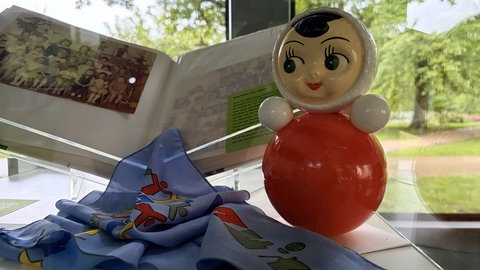 Ein Fotoalbum, ein Tuch und eine Puppe: Die Ausstellung "Bus der Habseligkeiten" zeigt Dinge, die Menschen auf ihrer Reise nach Deutschland mitgenommen haben.