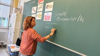Kinder sitzen im Stuhlkreis in einer Schule. Tina Rastätter und ihre Kolleginnen zeigen Kindern an Schulen, wie sie sich in schwierigen Situationen richtig verhalten.