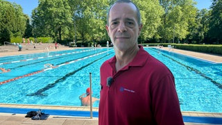 Ein Mann steht vor einem Schwimmbecken im Turmbergbad in Karlsruhe-Durlach.