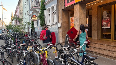 Zwei Menschen tragen alte Kinosessel aus der Schauburg in Karlsruhe.