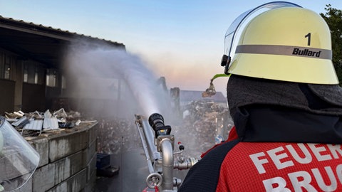 Ein Feuerwehrmann löscht den Brand in einem Bruchsaler Entsorgungsunternehmen
