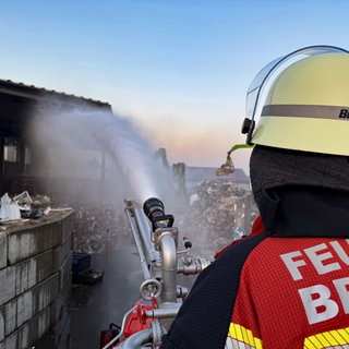 Ein Feuerwehrmann löscht den Brand in einem Bruchsaler Entsorgungsunternehmen