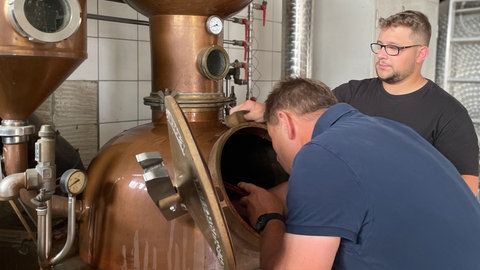 Zwei Männer arbeiten an einem Brennkessel für die Schnapsproduktion. Kleine Brennereien in der Ortenau stehen unter Druck