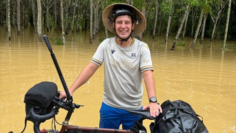 Ein Fahrradfahrer steht in kniehohem Wasser. 