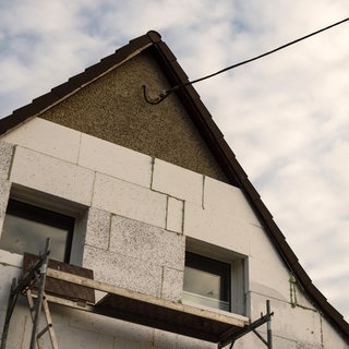(Symbolbild) Ein Haus aus den 1930er-Jahren wird mit Styroporplatten auf der Außenwand gedämmt. Eine Plattform aus Karlsruhe soll die Planug von energetischen Sanierungen vereinfachen.
