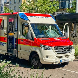 Ein Krankenwagen steht an einer Straße. Die Windschutzscheibe ist beschädigt. Der Rettungswagen ist mit einem Fahrradfahrer zusammengestoßen.