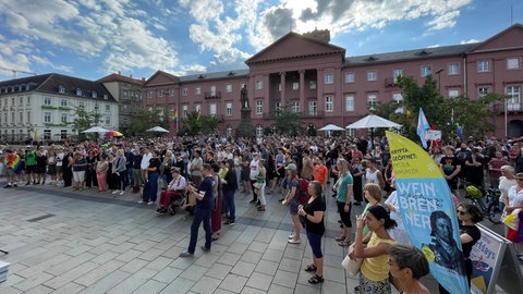 Menschen gedenken in Karlsruhe nach dem mutmaßlichen Anschlag beim CSD in Berlin.