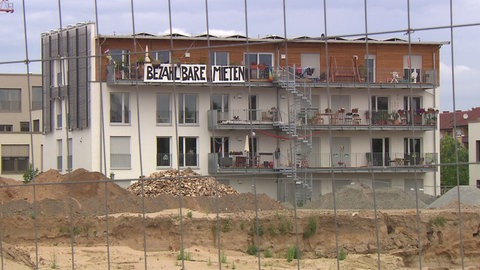 Ein Haus mit einem Banner mit der Aufschrift: "Bezahlbare Mieten". Die Sozialquote für Wohnungsmieten ist Thema im Mannheimer Gemeinderat