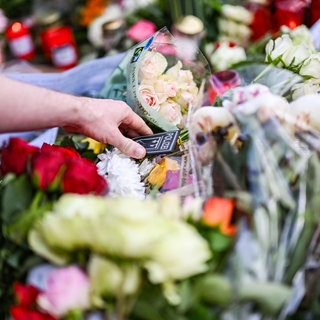 Ein Passant legt ein Polizeiwappen zu Blumen.