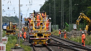 Arbeiter sind auf der Baustelle der Riedbahn mit schweren Baumaschinen im Einsatz
