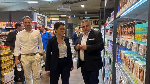 Der Gweschäfstführer des Nordbadischen Handelsverbandes Nordbaden, Swen Rubel (im Bild ganz links) und Supermarkt-Betreiber Sahin Karaaslan (rechts) führen die baden-württembergische Justizministerin Marion Gentges (CDU) durch einen Supermarkt in Mannheim.