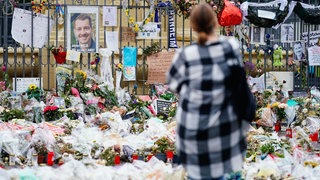 Eine Frau steht am Mannheimer Marktplatz an der Trauerstelle für den getöteten Polizisten Rouven Laur.