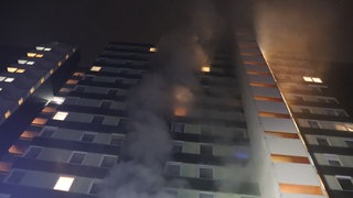 In einem 14-stöckigen Hochhaus im Heidelberger Stadtteil Emmertsgrund brennt es. Rauch steigt aus einem Fenster.