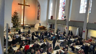 Das Foto zeigt die CityKirche Konkordien. An den Tischen sitzen Menschen und unterhalten sich.