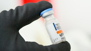 Ein Mitarbeiter hält im Werk der Roche Diagnostics GmbH eine Phiole mit dem Wirkstoff des Produkts Elevidys in der Hand.