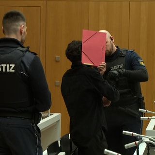 Ein Angeklagter wird in einen Gerichtssaal geführt