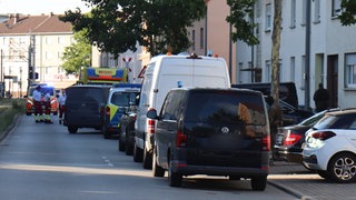 Bei einem Polizeieinsatz in Mannheim-Sandhofen stehen Rettungskräfte auf einer Straße