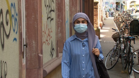 eine junge afghanische Frau läuft auf den Betrachter zu, sie trägt eine Kopfbedeckung und eine Maske.