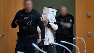 Ein Polizist führt Sulaiman A. für das Urteil in den Gerichtssaal des OLG Stuttgart-Stammheim.