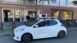 Ein weißes Scan-Auto mit Kameras auf dem Dach in Heidelberg