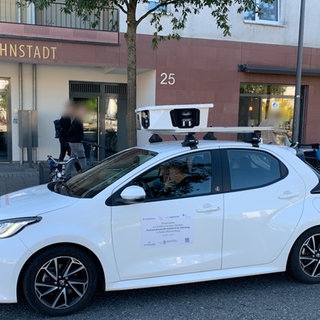 Ein weißes Scan-Auto mit Kameras auf dem Dach in Heidelberg