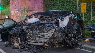 Ein schwarzes Autowrack vor einem Brückenpfeiler