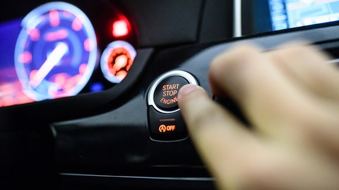 Ein Mann drückt den Start-Stop-Knopf eines Autos (Symbolbild).
