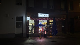 In einem Kiosk ist ein Mitarbeiter der Kriminaltechnik im Einsatz.