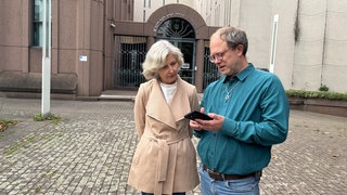 Die Vorsitzende der Jüdischen Gemeinde Mannheim, Deborah Kämper, und der Vorsitzende der Deutsch-Israelischen Gesellschaft Arbeitsgemeinschaft Rhein-NeckarMannheim, Chris Rihm, lesen aktuelle Nachrichten zum Friedensplan vor der Mannheimer Synagoge.
