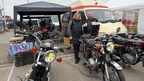 Aussteller auf der Veterama Mannheim 2025 auf dem Maimarktgelände kommen aus ganz Europa. wie Sabine und Wolfgang aus der Eifel. Sie stehen hinter mehreren Motorrädern, die sie verkaufen.