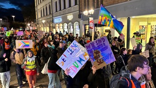 Demonstrierende ziehen mit Bannern und Fahnen durch die dunkle Heidelberger Hauptstraße